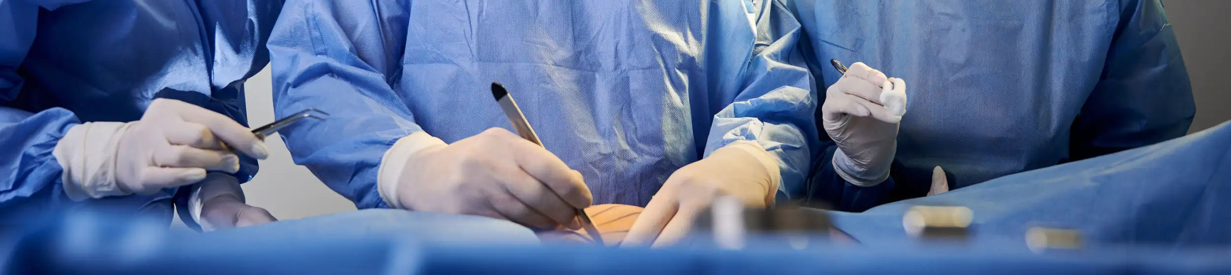 Blue surgical gowns worn by medical professionals during an operation.